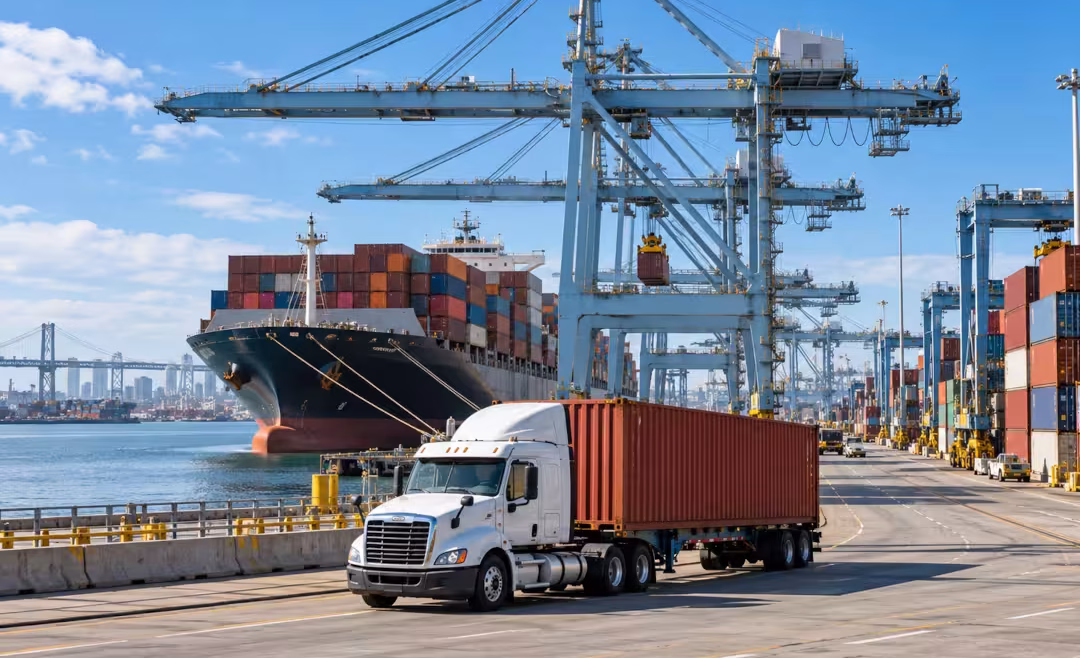 fotografía de un camión cargando un contendor y un barco en el muelle